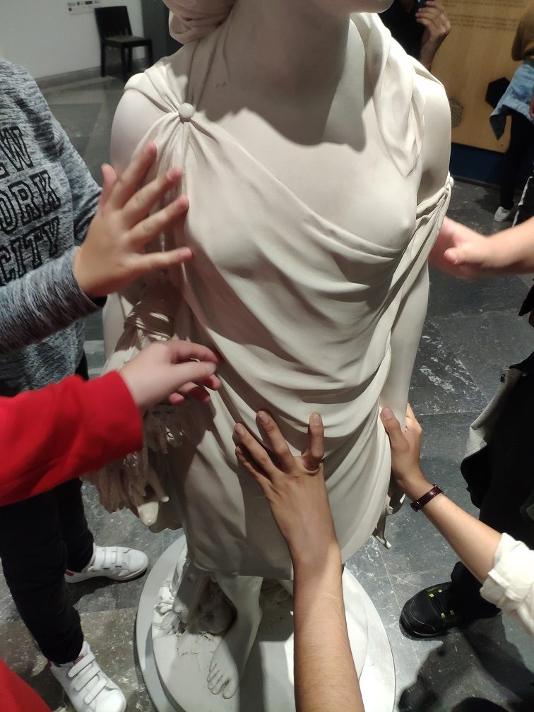 Des mains touchent une reproduction d'une sculpture